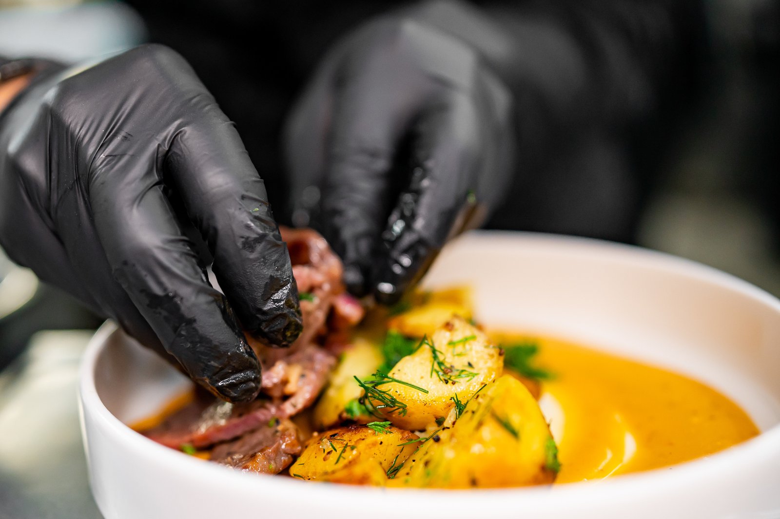 Chef cook hand cooking potato and meat salad at the restaurant kitchen